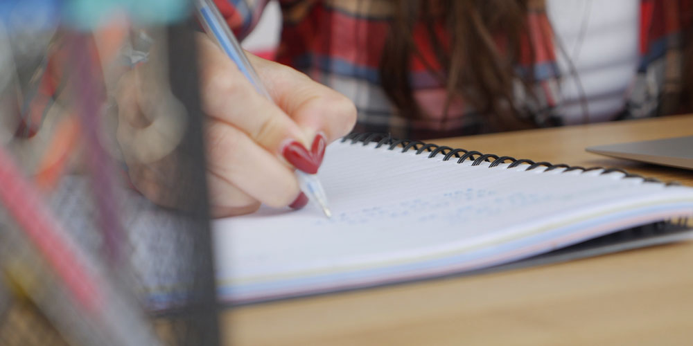 Student writing on notebook
